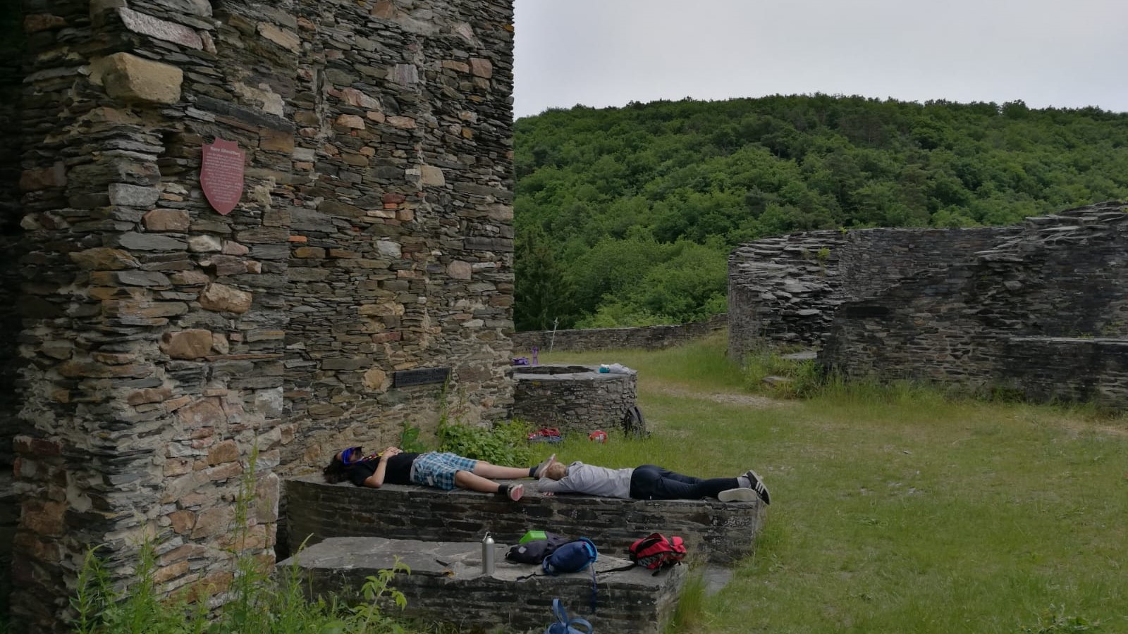 Zwei Personen liegen auf der Mauer einer Burgruine